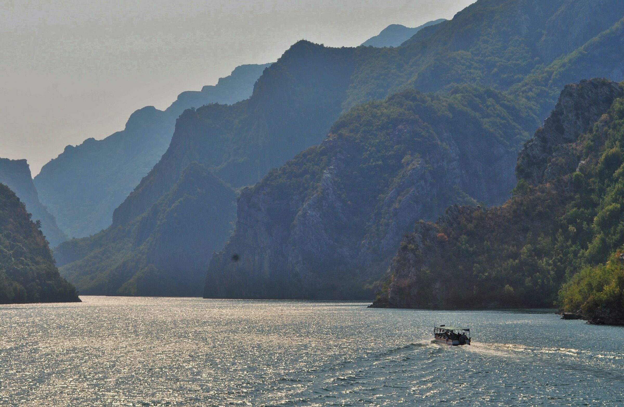 Boat on Lake Koman between steep mountain walls