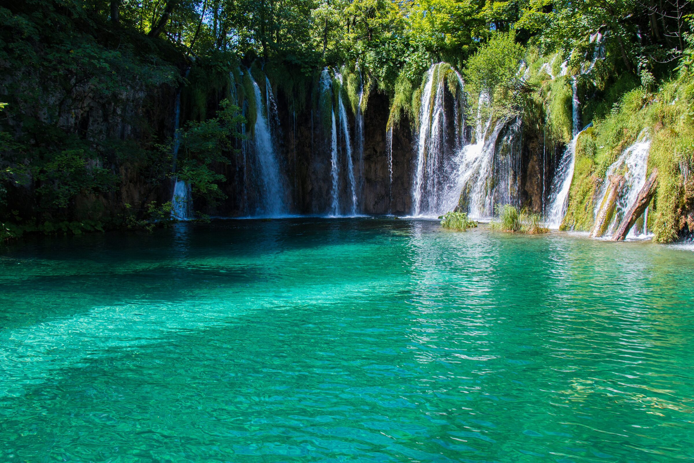 Waterfalls falling into a turquoise lake at Plitvice